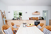 Dining table and wicker chairs in front of kitchen units