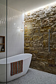 Frei stehende Badewanne im Badezimmer mit Sandsteinwand