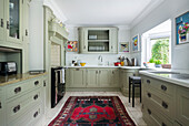 Kitchen with light green fitted cupboards
