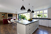 A white kitchen island and a kitchen counter under a window in an open-plan living room