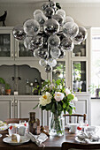 Set table with bouquet of flowers, above it pendant light with glass spheres