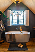 Freestanding bathtub in attic with Christmas decorations and warm wood tones