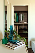 A view into open wardrobe over a sideboard with glass vases