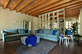 A lounge with a blue sofa suite and a wooden ceiling