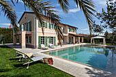 Sunbeds by the pool, in the background villa with green shutters