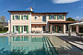 A pool and a villa with green shutters