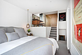 Double bed in sleeping area, stairs leading to mezzanine with dressing vanity and glass partition