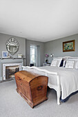 White queen sized bed and old wooden chest in the bedroom with grey walls