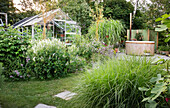 Summer garden with outdoor spa and greenhouse in the background