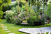 Curved wooden terrace and lush flowers in a summer garden