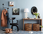 Console table, designer chair and coat rack in the hallway with blue walls