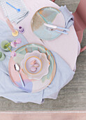 Pastellfarbenes Gedeck auf Tisch mit Tulpen und Kerze