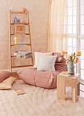 Comfortable relax chair next to ladder with decorative objects in the room in soft tones