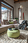 Light sofa set and pouf on wool carpet in front of panoramic window