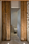 Tür mit Blick ins Badezimmer zwischen Massivholzbalken