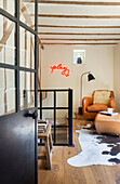 View through open industrial door to cognac colored leather armchair and stool on cowhide