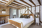 Double bed in bedroom with exposed brickwork and wood-beamed ceiling