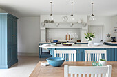Dining area in white kitchen with blue cabinet fronts