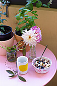 Rosa Frühstückstisch mit Blumen und Topfpflanzen auf dem Balkon