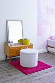Mid Century dressing table with mirror, in front of it seat pouf and carpet rug in pink