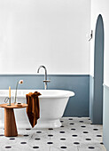 Frei stehende Badewanne mit Standarmatur und Beistelltisch im Badezimmer mit Marmor-Bodenfliesen