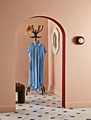 Rounded archway with view of coat rack with blue shirt dress