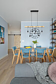 View of dining area with blue chairs in front of light blue wall in open plan living room