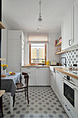 White fitted kitchen with dining area and patterned tiles