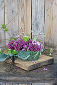 Lilac arrangement in bowl with kohlrabi leaves and stems to help with placement