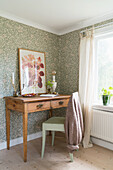 Wooden desk with two drawers in wallpapered guest room