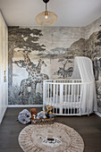 White cot in children's room with wallpaper in safari motif