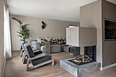 Grey armchairs and sofa set with throw pillows in light living room, room divider wall with fireplace