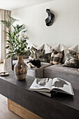 View over coffee table with flower to grey sofa set with throw pillows