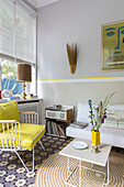 Classic armchair with yellow canvas cover and white sofa in the conservatory