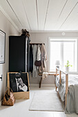 Bright bedroom with double bed, antique wardrobe and black and white photo