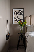 Beige getönte Schlafzimmer mit Einbauschrank, Hocker und Poster neben dem Bett