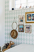 Wallpapered wall with framed maps, animal figures on windowsill in children's room