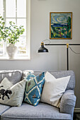 Cozy upholstered sofa, lamp and painting above it