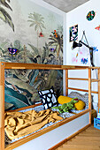 Bed with wooden frame in front of poster with jungle motif