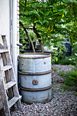 Old rain barrel and painter's ladder on the house wall