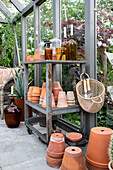 Old shelf with terracotta pots, bottles and candles in the greenhouse