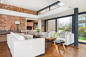 Lounge with light-colored seating with floor to ceiling windows and brick wall