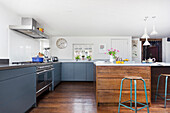 Moderne Einbauküche mit graublauen Schrankfronten und Kücheninsel mit rustikaler Holzfront