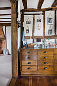 Antique bureau with framed photos above in a room with rustic wooden beams
