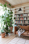 Modern living room with light wood elements, leather sofa, and indoor plants