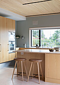 Kitchen counter with light wood fronts and counter height bar stools