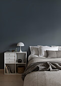 Queen bed and nightstand in front of a grey wall