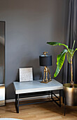 Low console with giraffe lamp and houseplant in front of grey wall