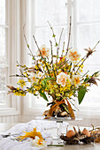 Spring bouquet of forsythia and daffodils (Narcissus) decorated with eggs in a nest, Easter decoration