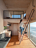 Sleeping loft above the kitchen in the wooden house woman on ladder